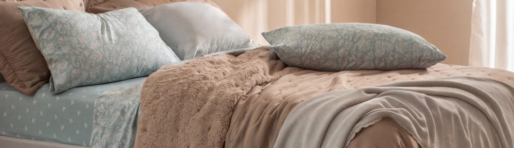 Cama vestida en capas con texturas y tonos neutros, frazada Coral Fleece y piecera de Arredo